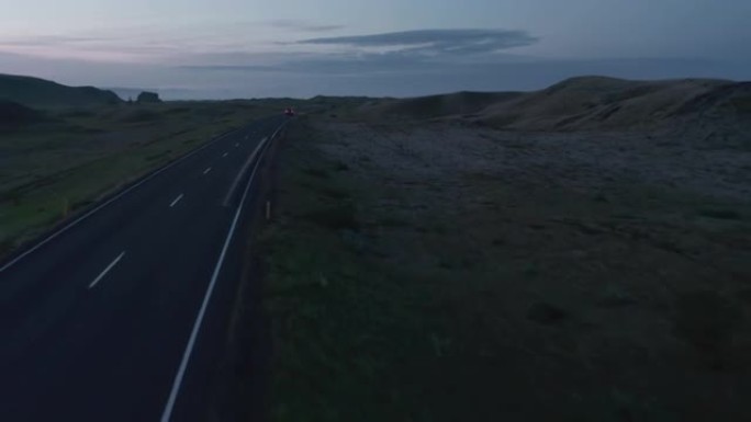 在北欧乡村公路上行驶的汽车的前瞻性跟踪。黄昏时的全景景观。冰岛