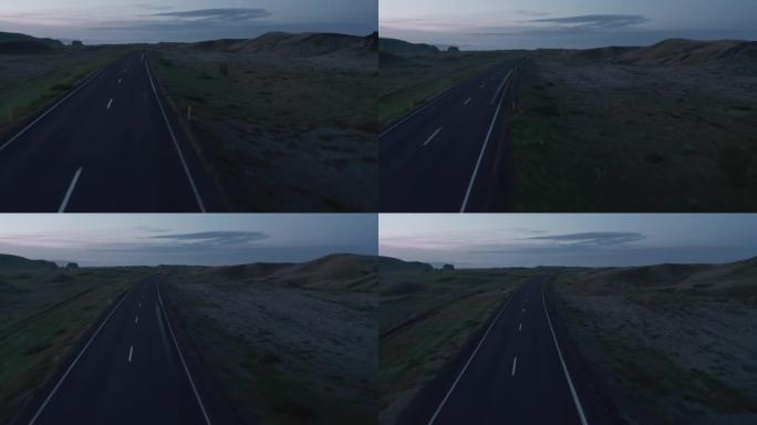 在北欧乡村公路上行驶的汽车的前瞻性跟踪。黄昏时的全景景观。冰岛