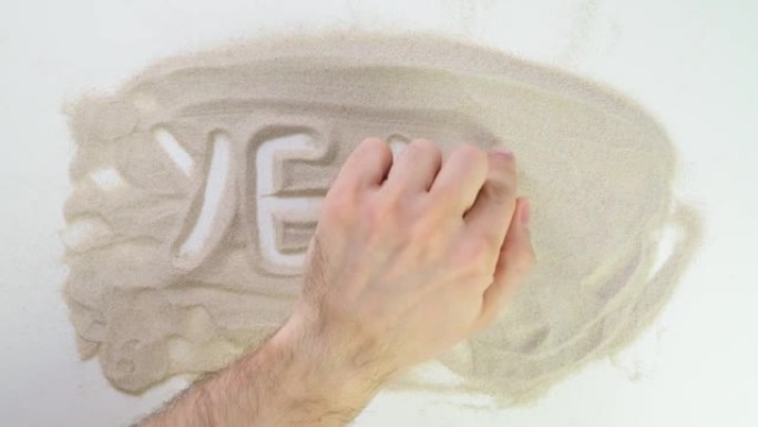 俯视图在沙滩上画。高加索人用米色沙子书写文字。度假和旅行。海滩度假。沙画。来自天然材料的创造力。