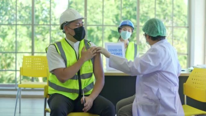 女医生在医院用注射器给亚洲工人注射新冠病毒疫苗，以防止欧米克隆冠状病毒的爆发
