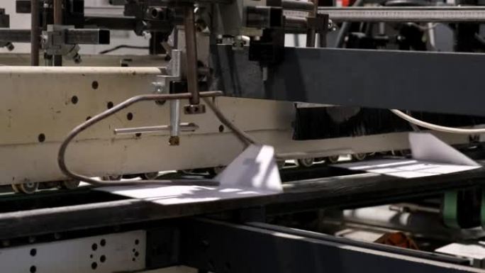 生产纸箱的工厂。自动折叠和胶合线。传送带上的纸板箱。折叠盒子特写。