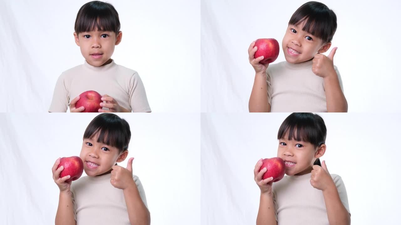快乐的苹果小女孩。可爱的亚洲小女孩在工作室吃白色背景的有机苹果。儿童健康营养。