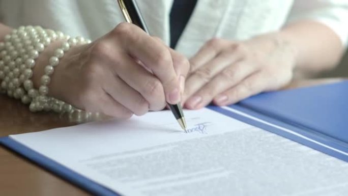 女商人签署合同，法律协议，文件。穿着白衬衫的女商人坐在办公室的工作场所，签署了许多文件