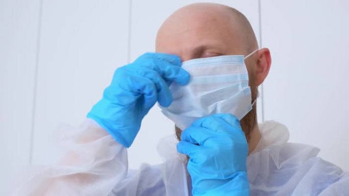 医生戴上口罩和眼镜，穿着无菌衣服和手套。一名卫生工作者在患有冠状病毒患者的地区辛苦工作。病人的治疗