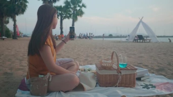 女人在海滩上的毯子上吃食物和野餐