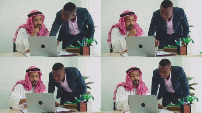 中东商人和非洲商人开会并使用笔记本电脑在办公室工作