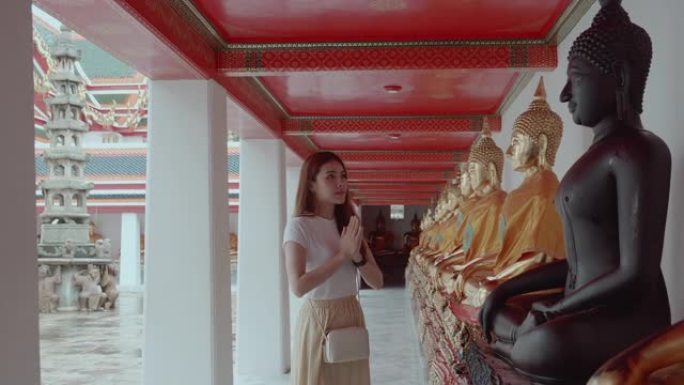 一位美丽的年轻女子在泰国曼谷的Wat Pho向佛陀致敬。地标/著名景点意外拍摄。