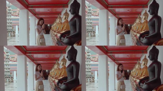 一位美丽的年轻女子在泰国曼谷的Wat Pho向佛陀致敬。地标/著名景点意外拍摄。