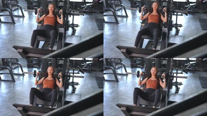 一名亚洲女性在健身房锻炼身体，在健身时间用减肥器械锻炼身体。