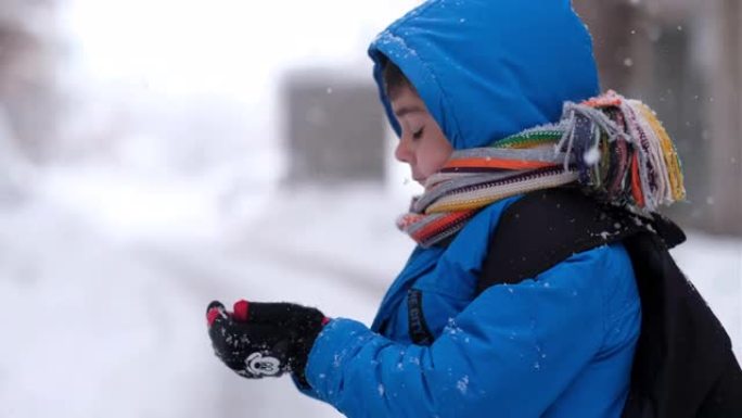 穿着蓝色冬装的有趣小男孩在降雪时行走。儿童户外冬季活动