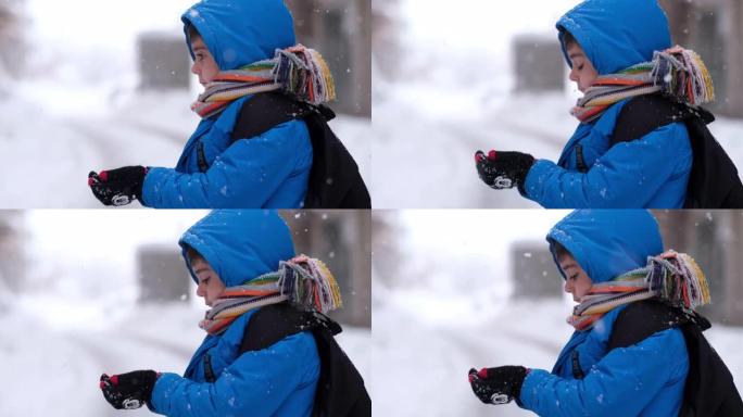 穿着蓝色冬装的有趣小男孩在降雪时行走。儿童户外冬季活动