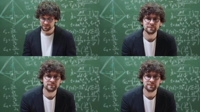 肖像智能时尚的老师戴着眼镜站在大学或学校的教室里看着相机，微笑着，黑板上有垫子公式背景。教育和学习理
