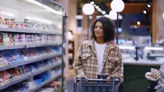 微笑的非洲裔美国妇女带着手推车穿过超市