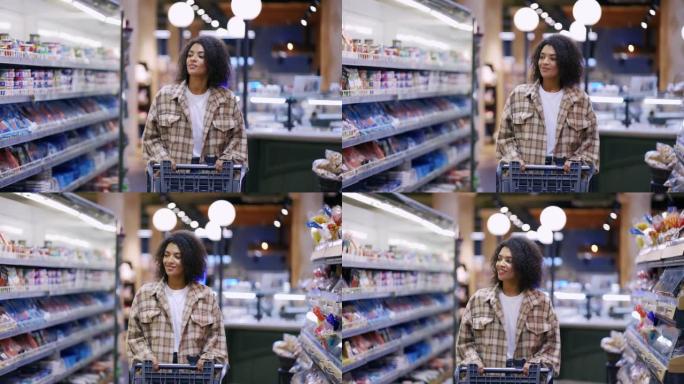 微笑的非洲裔美国妇女带着手推车穿过超市