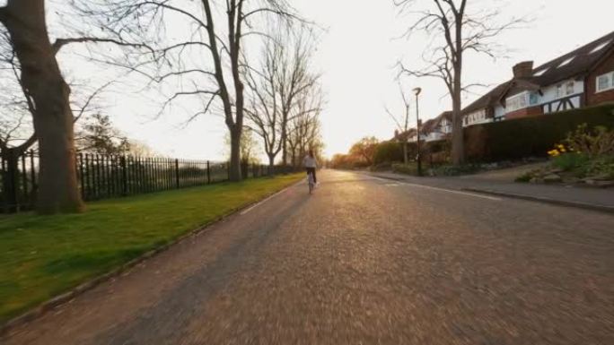 日出时，年轻女子在居民区空旷的道路上骑自行车