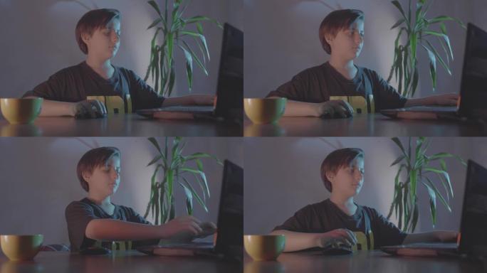 慢动作少年在笔记本电脑上工作。蓝色范围内的增强配色方案