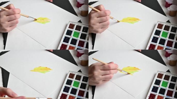 艺术家在白色纸上用黄色和绿色水彩画绘画