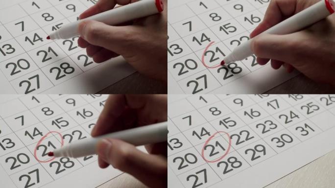 人的手用红笔在纸质日历上写下第21天。