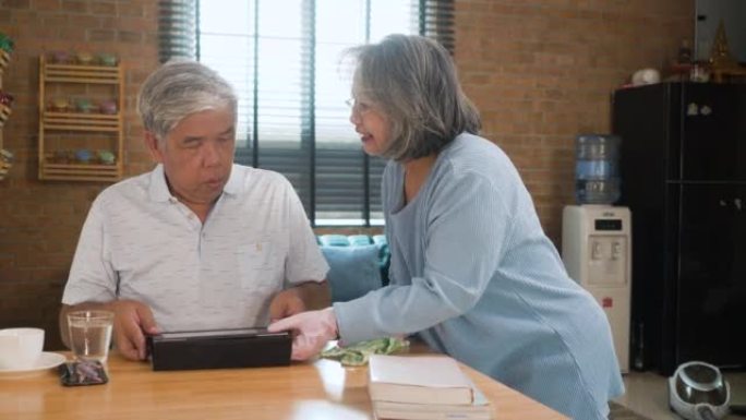 老年人健康生活理念。老人打扫桌子。老人在家使用数字平板电脑。成熟的女人用抹布擦木桌。