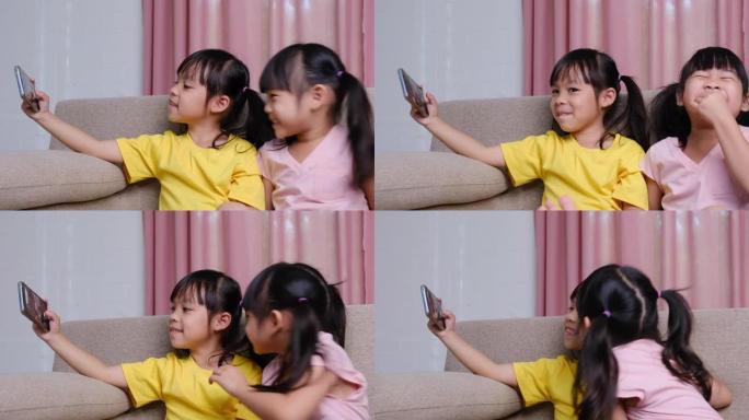 两个姐妹正坐在家里沙发上的智能手机上自拍。