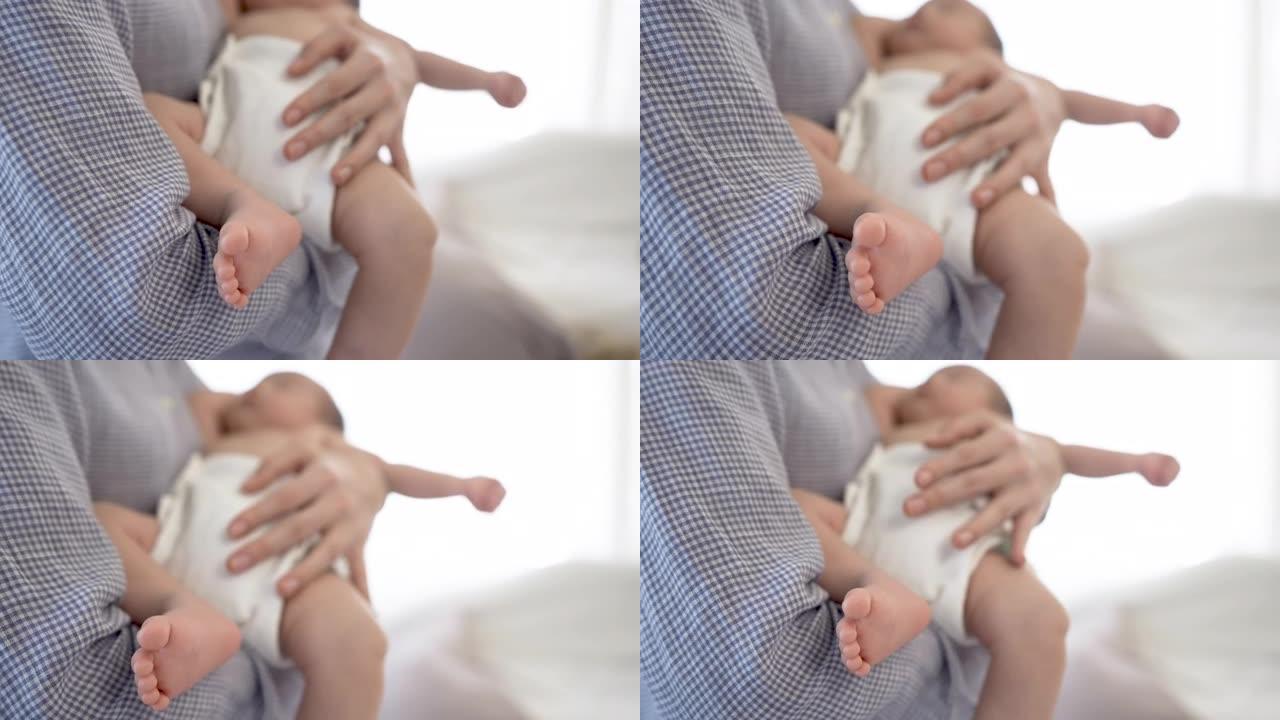 一个2个月大的亚洲新生男孩的脚在母亲的腿上的4k特写镜头，由母亲的手严密保护。