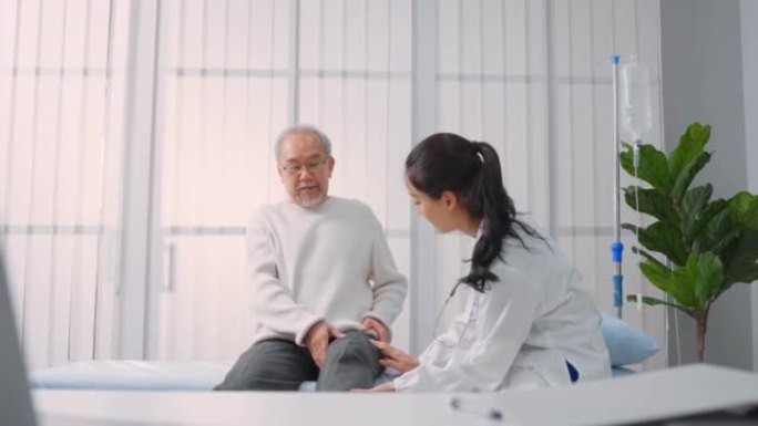 亚洲女医生为老年男性患者做腿部抬高运动。有吸引力的女性专科医生为老年成熟男性做物理治疗程序，以伸展和