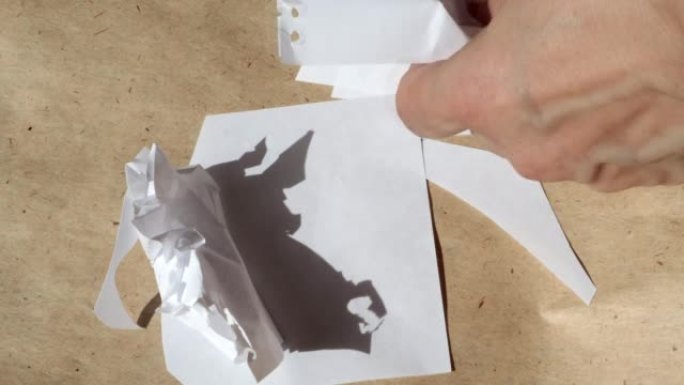 4k视频，一个女人的手在棕色牛皮纸的背景下皱起白纸。特写