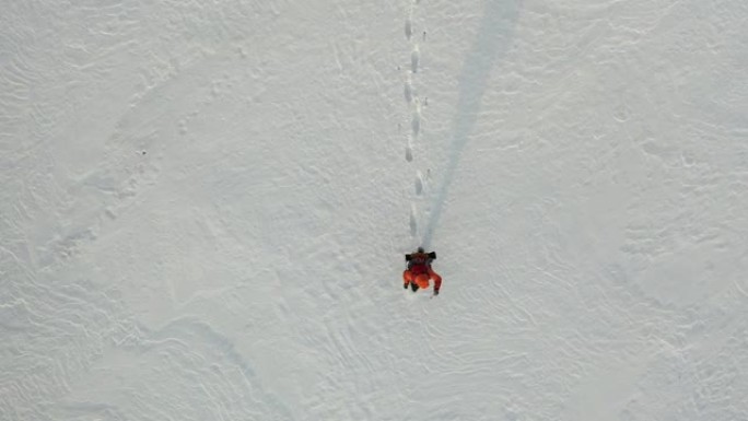 俯视图-一个背着背包的孤独旅行者穿过白雪皑皑的沙漠。在极冷条件下生存的概念