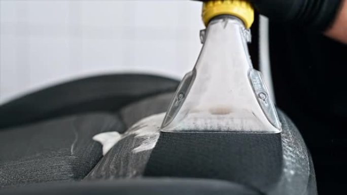 洗车处的工作清洁工。使用专业真空吸尘器清洁座椅。慢动作
