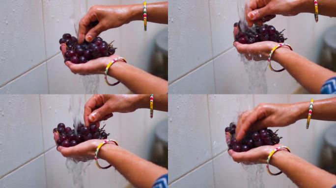 印度女性双手在家里水龙头的水流下洗葡萄果实的特写镜头。洗水果和蔬菜，保健。
