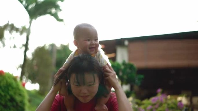 亚洲母亲在日落时将婴儿抱在肩上
