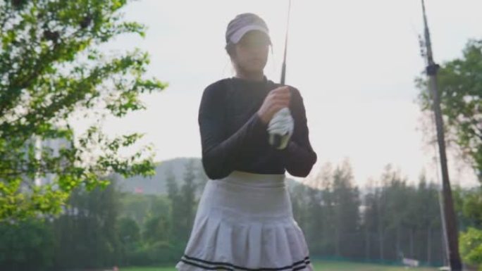 高尔夫比赛前手持俱乐部训练运动女士。