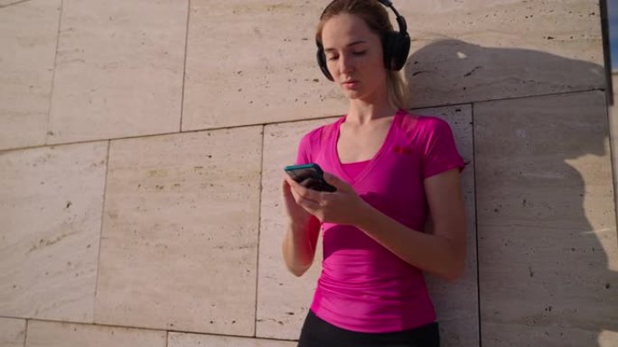 年轻女子正在通过无线耳机听音乐，在智能手机中切换歌曲