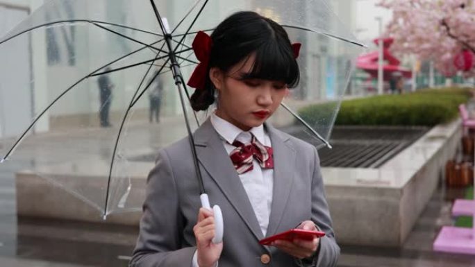 亚籍女学生撑伞走路肖像看手机资讯