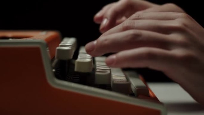 人的手在复古打字机特写上打字，手指按下黑色背景上老式打字机键盘的按钮