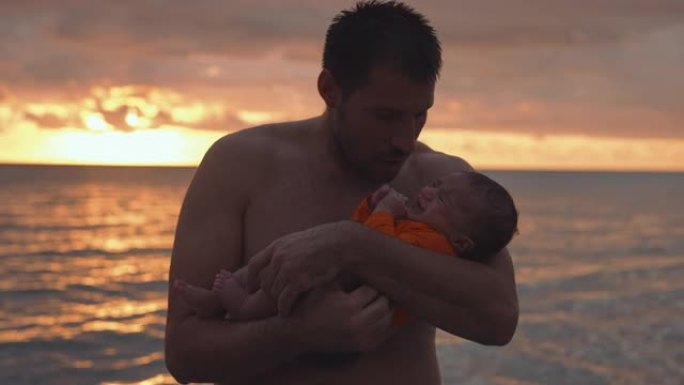 慈爱的父亲在海滩上抱着婴儿的儿子