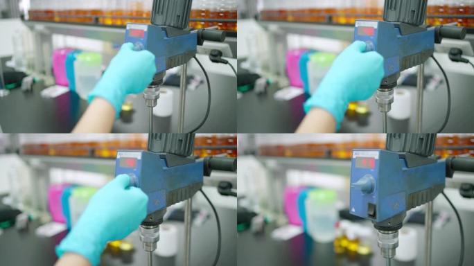 科学家戴丁腈手套的特写镜头在润滑剂实验室调节机械搅拌器的速度。分析和测试油的质量。发展与研究理念