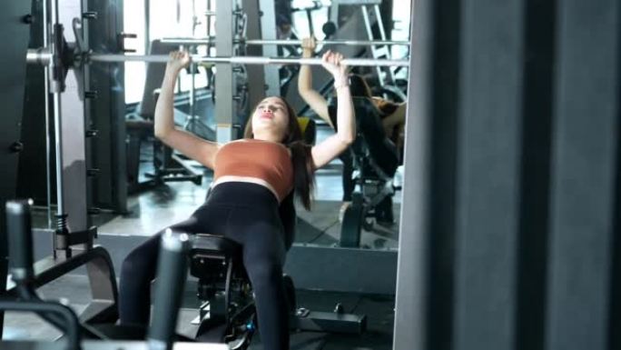 一名亚洲女性在健身房锻炼身体，在健身时间用减肥器械锻炼身体。