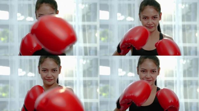 穿着红色手套的运动型亚洲女孩正在做一个有趣的拳击锻炼。