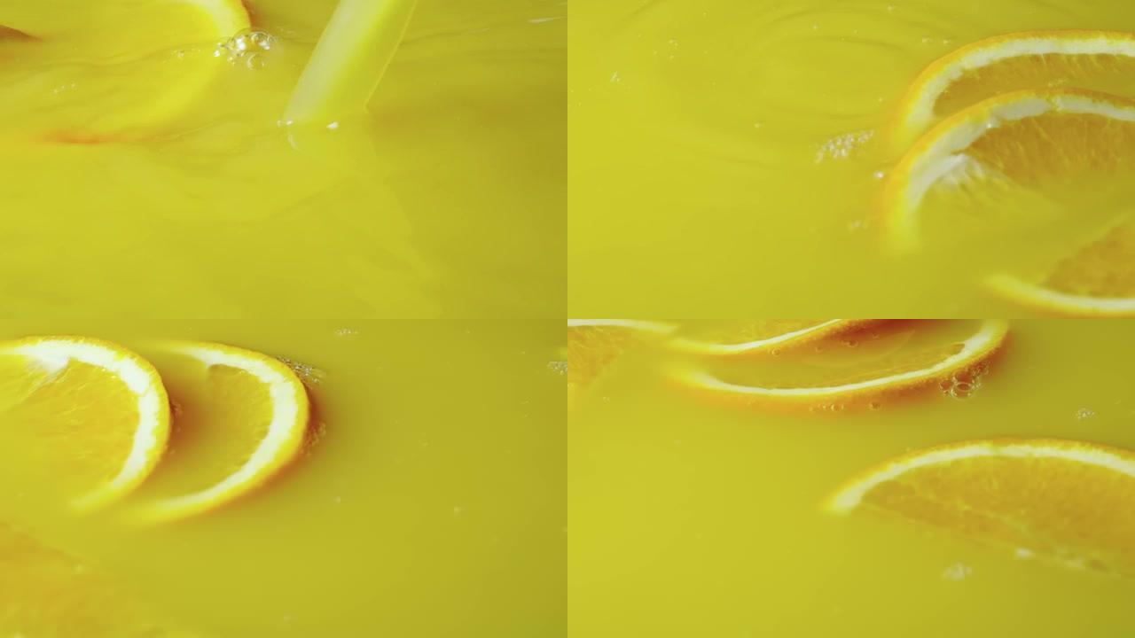 黄色橙汁配橙子水果两半。关闭柑橘异国甜花蜜，橙色切片在液体中旋转。早餐用热带鲜榨饮料的背景。慢动作