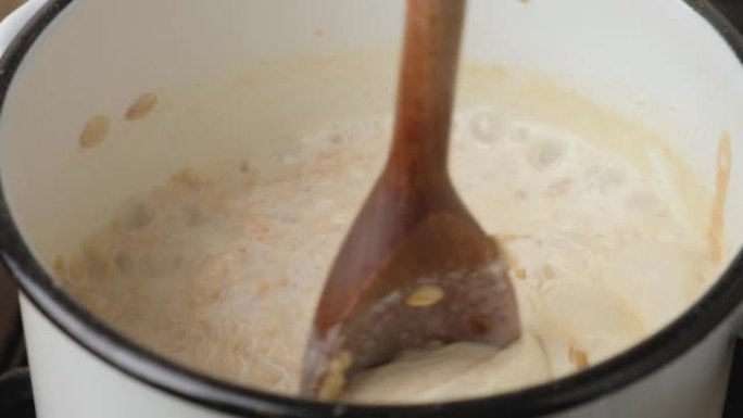 在锅中煮燕麦片煮粥，然后用木勺搅拌。健康早餐