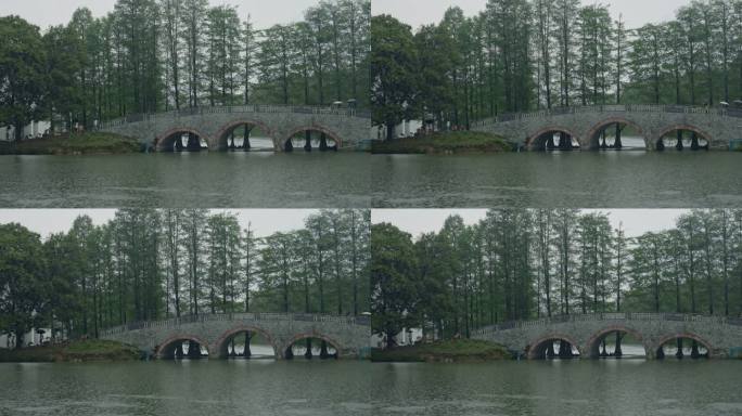 4K实拍春雨中公园湖边的拱桥上撑伞的游人