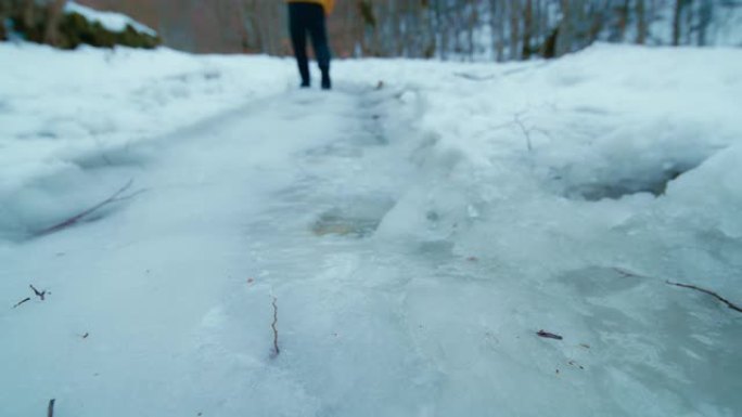 男子走在一条山间小道上的鞋印融化的冰旁边，POV，低角度视图。