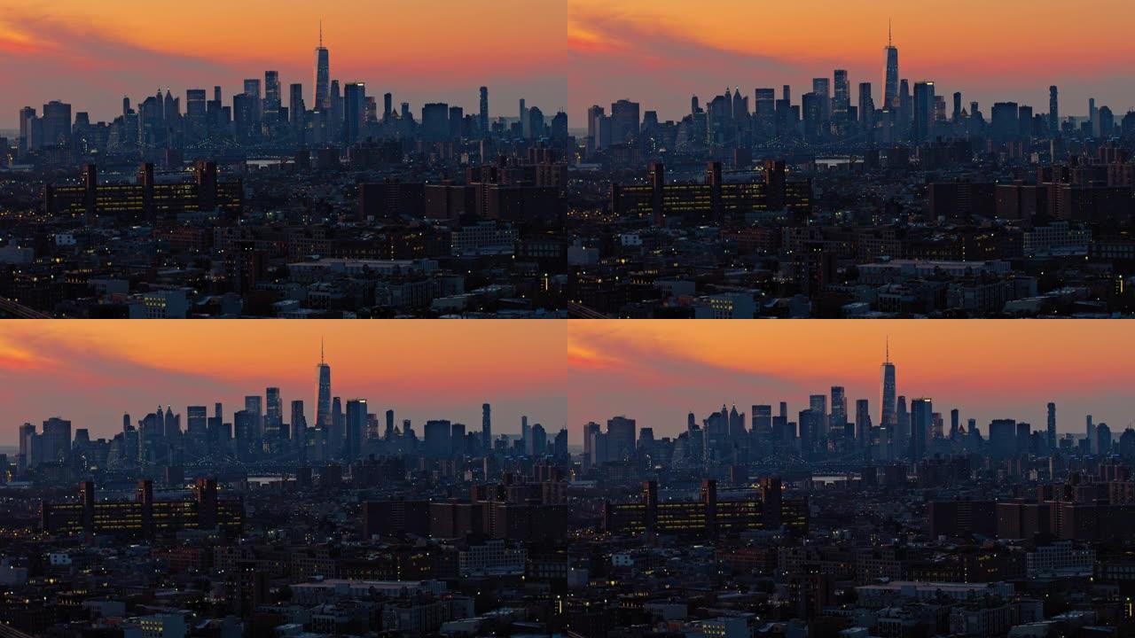 曼哈顿市中心和自由塔在夜晚照亮。日落时分，布鲁克林住宅区的远处景色，天空充满戏剧性。航拍镜头的移动速