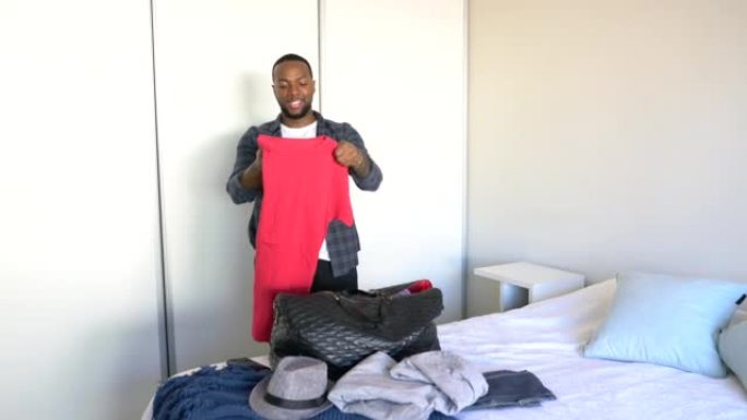 黑人在酒店卧室用衣服打包行李