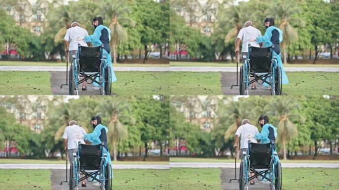 后视图亚洲华裔女性理疗师帮助高级男子从轮椅上站起来，用拐杖在公园散步