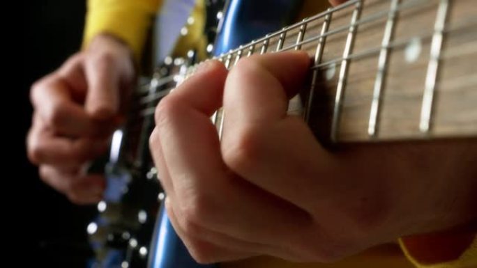 男吉他手在蓝色电吉他上用拨子弹指。
