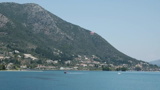 地中海岛屿景观。快艇，游客在降落伞后沿着海岸线飞行