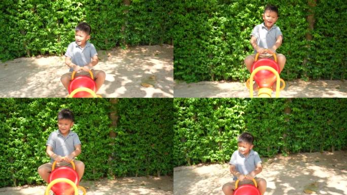 亚洲小子在户外操场玩秋千、跷跷板和活动。户外学习、发现和幸福的概念