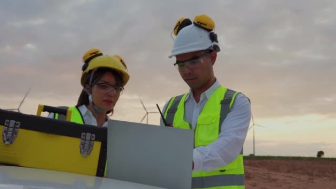 两名工程师使用数字平板电脑检查风车在风力涡轮机农场，绿色能源概念。